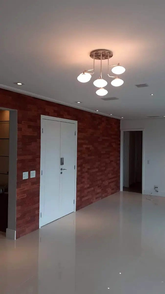 Sala com parede em tijolo aparente, obra entregue pela FC